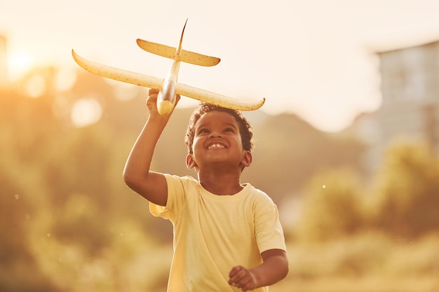 With toy in hands African american kid have fun in the field at summer daytime