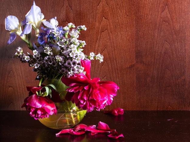 Withered flowers in vase on dark brown background