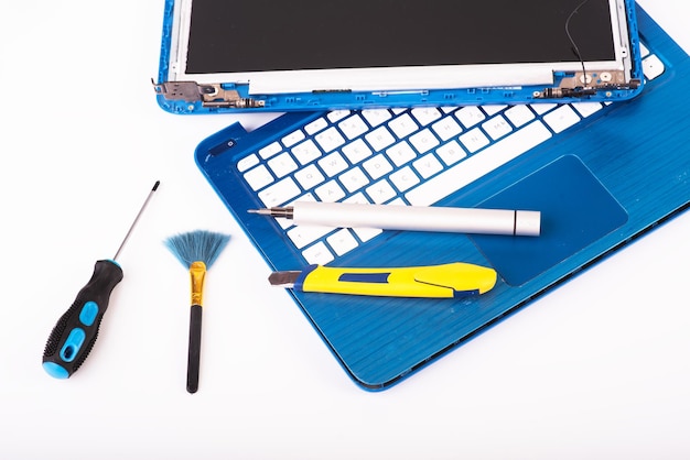 Wizard repairs laptop with tools and hands on the blue wooding table top view