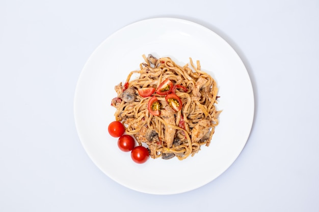 Wok food on a white ceramic plate is tasty and fresh with sauce on a light isolated background