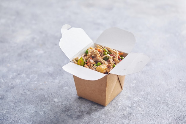 Wok with turkey meat soba noodles paprika mushrooms and carrot in takeout box