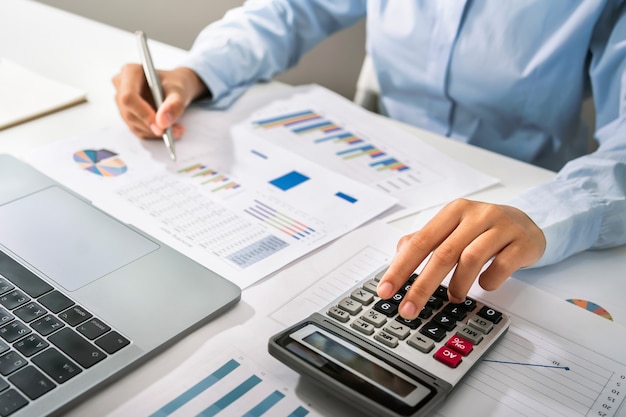 Woman accountant use calculator and computer with holding pen on desk in office. finance and accounting concept