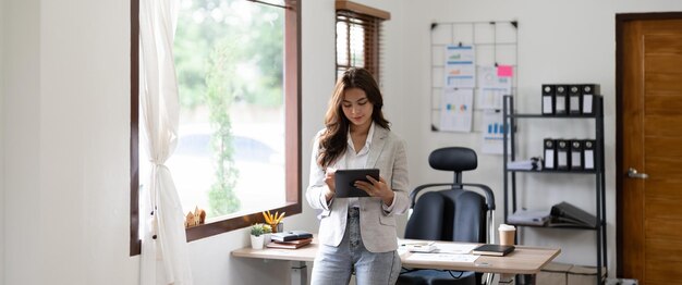 Woman accountant using calculator and digital tablet computer in office finance and accounting concept