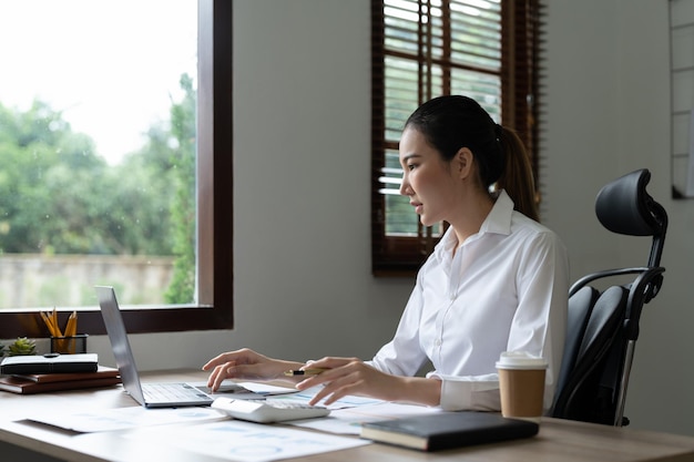 Woman accountant using calculator and laptop computer in office finance and accounting concept