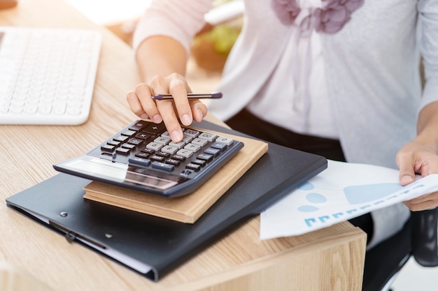 Woman accountant working on accounts in business analysis with graphs and document  financial data report with laptop computer at office, business concept.