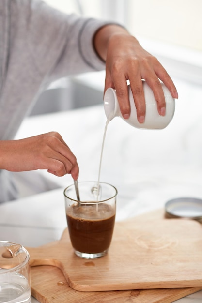 Woman adding milk in mug with cocoa