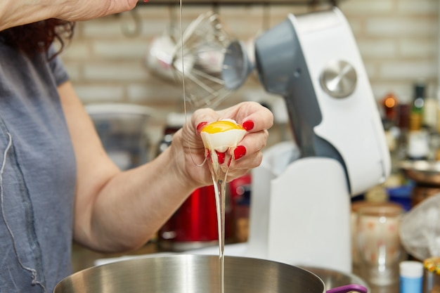 Woman adds an egg to dough to make cheese pie with zest, a step-by-step recipe from the internet.