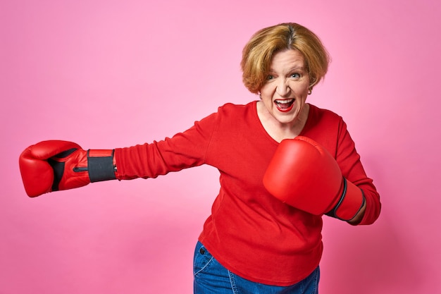 Woman aged in boxing gloves. The concept of the fight against old age.