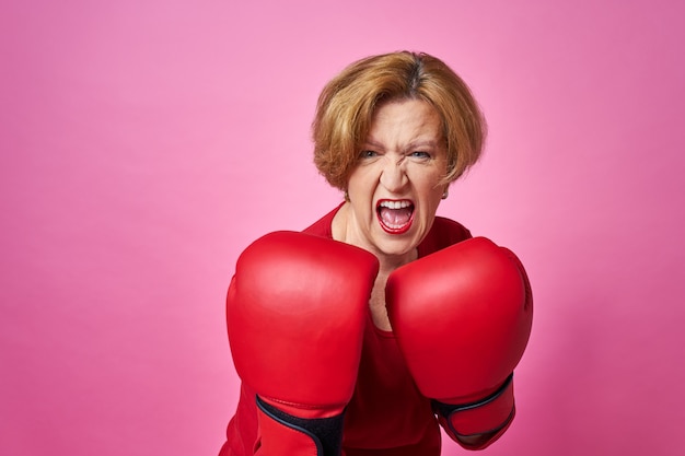 Woman aged in boxing gloves. The concept of the fight against old age.