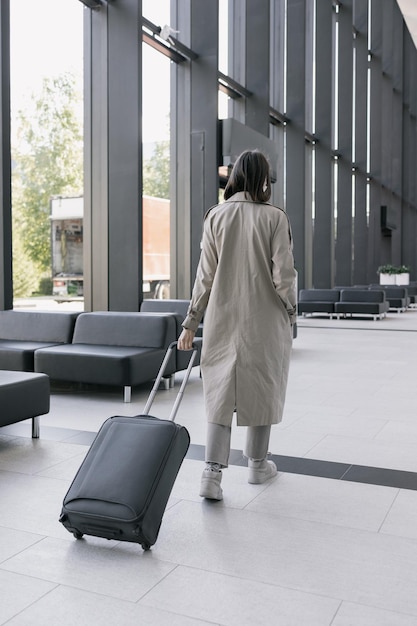 Woman at the airport or congress center with a suitcase is sitting in the waiting area and chatting