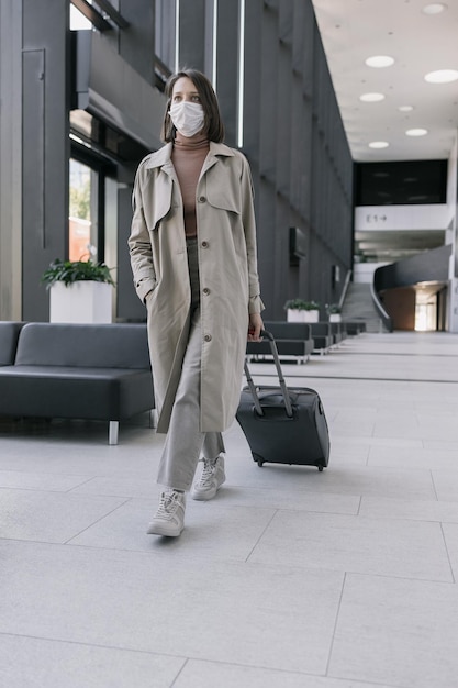 Woman at the airport or congress center with a suitcase is sitting in the waiting area and chatting