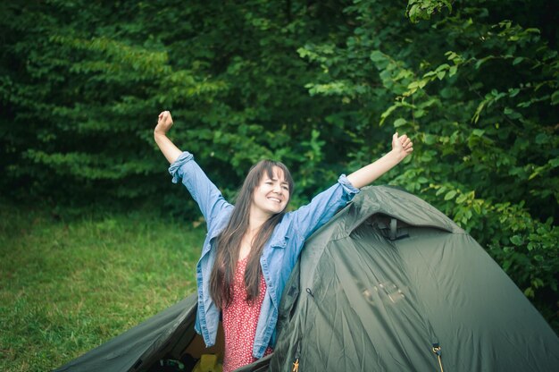 Photo woman among the mountains near the tent enjoys nature