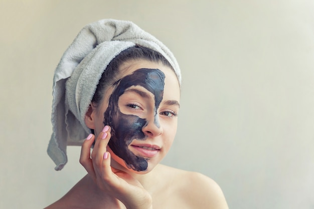 Woman applying black nourishing mask on face