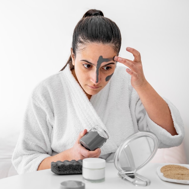 Woman applying clay face mask