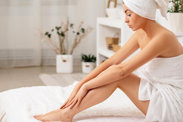 Woman applying cream on her legs