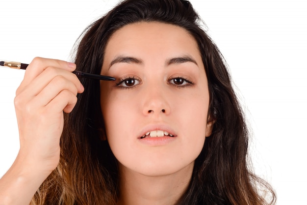 Woman applying eyeshadow on studio.