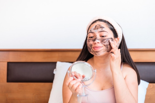 A woman applying a face mask in front of a mirror.