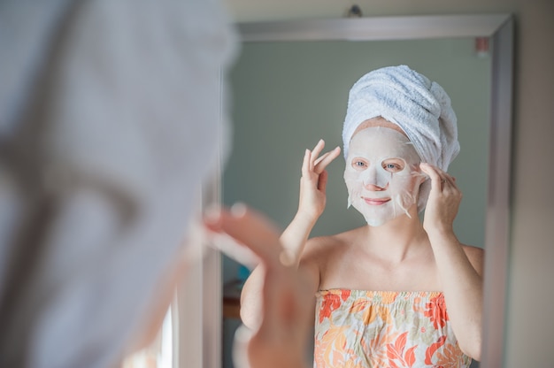 woman applying a facial mask sheet