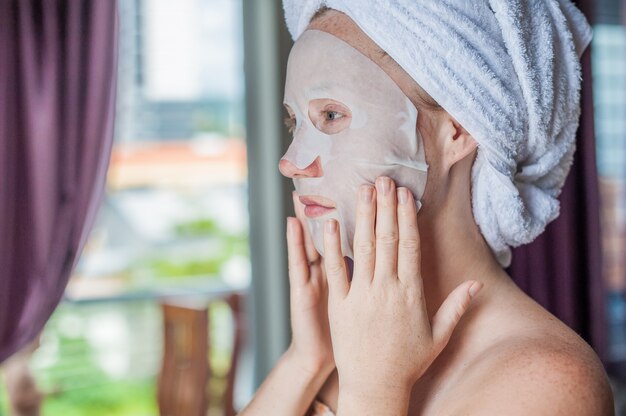 woman applying a facial mask sheet