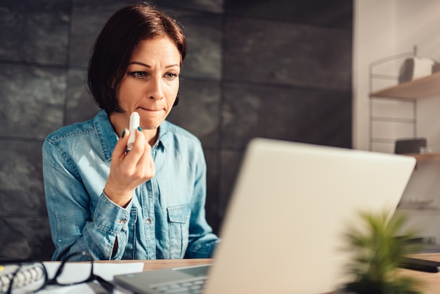 Woman applying lip balm at work