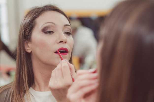 Photo woman applying lipstick while looking in mirror