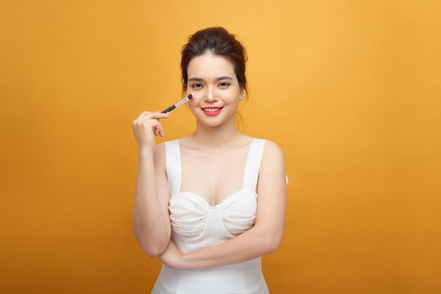 Woman applying make up with brush, isolated. Beauty procedures