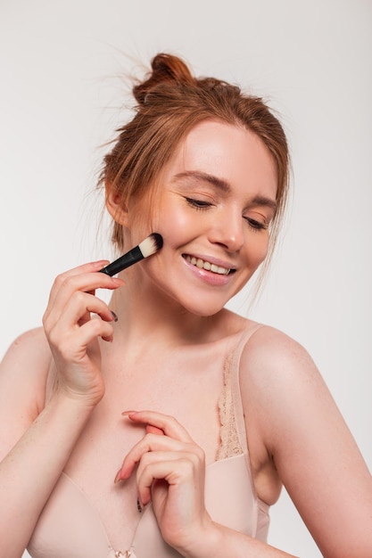 A woman applying makeup with a brush.