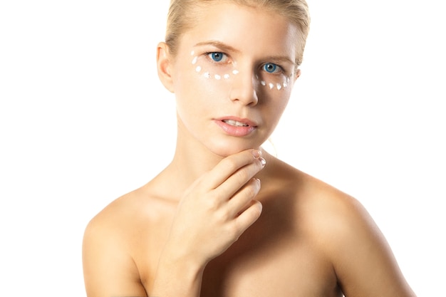 Woman applying moisturizer cream on face isolated