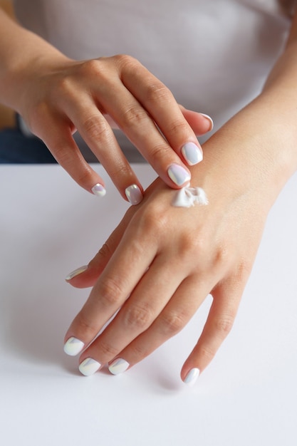 Woman applying moisturizer to her hands. Hand skin care. Health and beauty concept