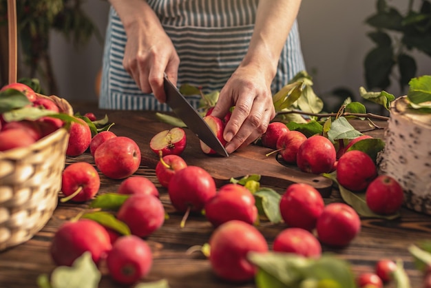 Woman in an apron in the kitchen is cutting appetizing red apples from a fresh harvest Concept of an autumn cozy atmosphere cooking dishes from organic healthy apples from own garden