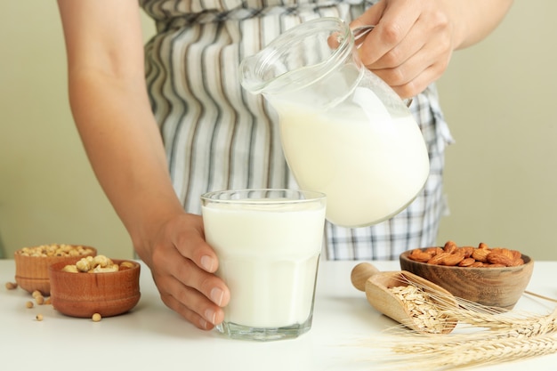 Woman in apron pours milk into a glass