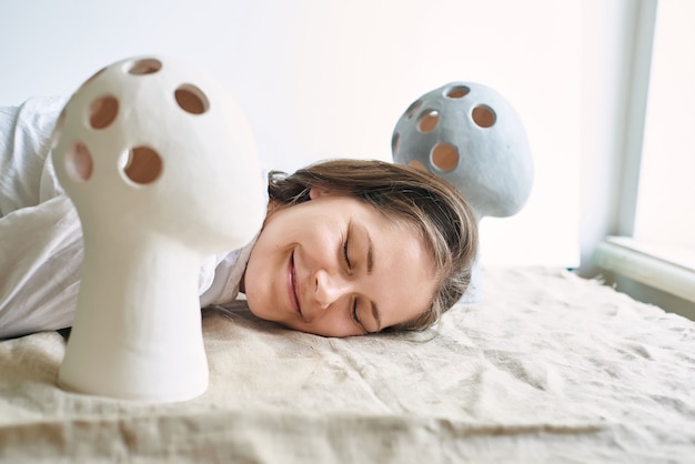 Woman artisan ceramist against the background of unusual vases in the form of a human head