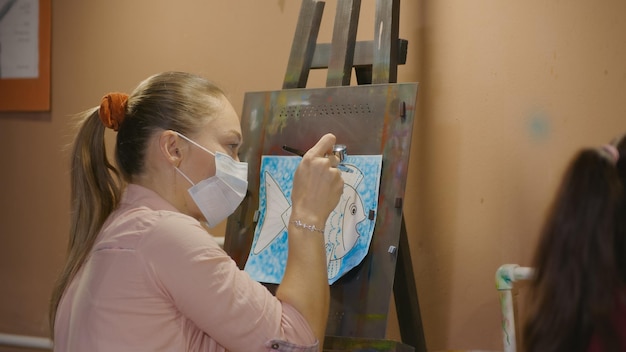 Woman artist learns to paint with airbrush with acrylic dye paper and easel