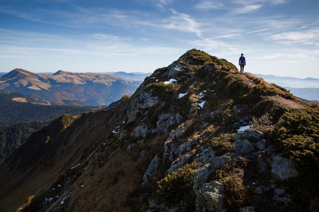 Woman ascending peak of the mountain