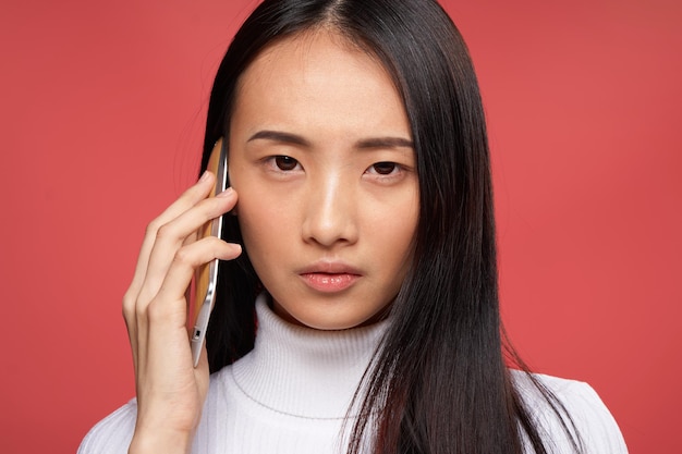 Woman of asian appearance talking on the phone technology emotions red background