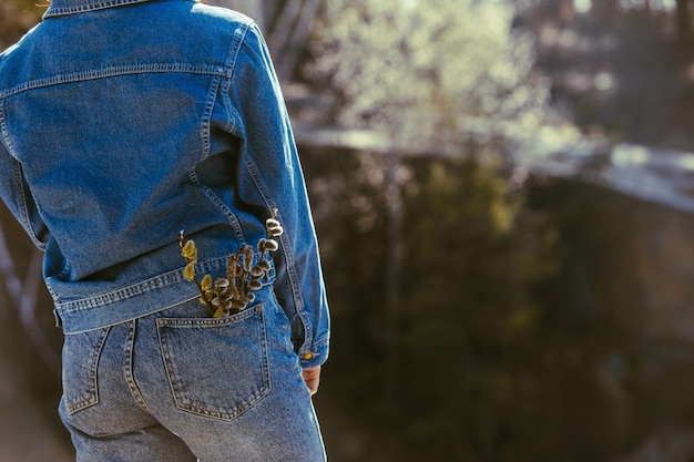 Woman ass in jeans blooming flowers in pocket view from behind