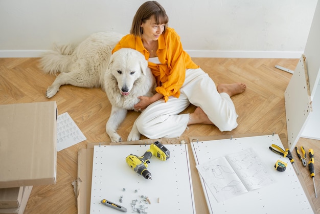 Woman assembles furniture at home with dog