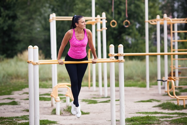 woman athlete engaged on the horizontal bar in the street