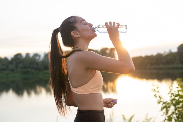 Woman athlete takes a break, she drinking water, out on a run on a hot day