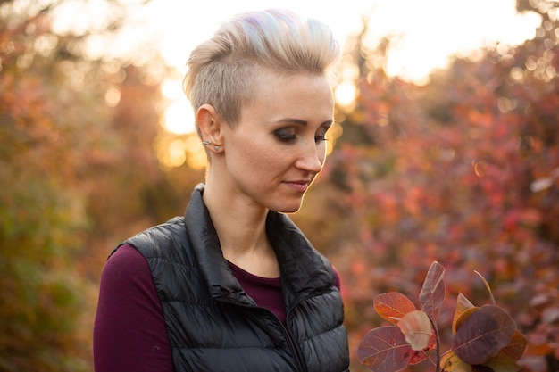 Woman in autumn forest background with golden and red trees wearing grey sweater