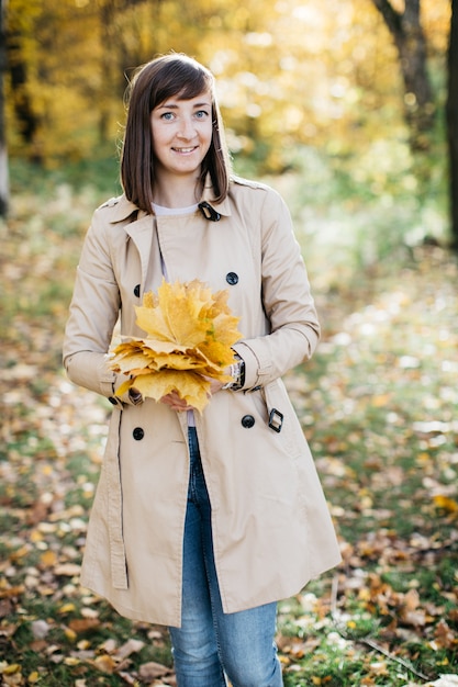 Woman in the autumn forest with leaves in her hands The woman is happy