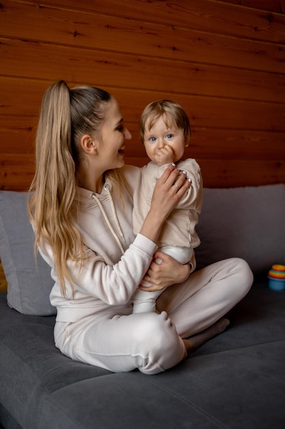 A woman and a baby are sitting on a bed and the woman is holding her baby.