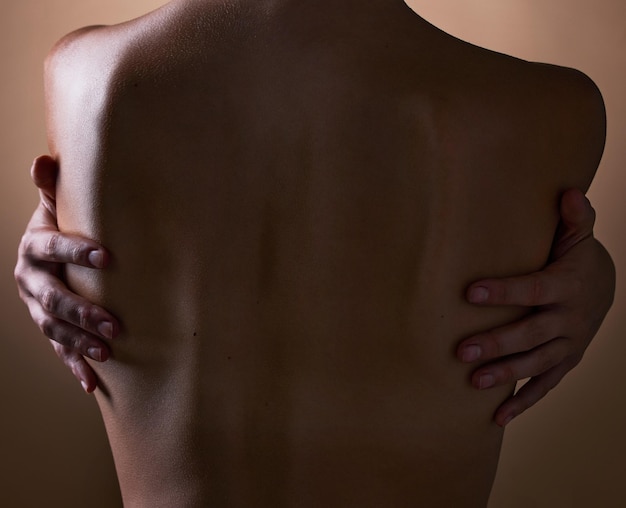 Photo woman back and hands touching body on brown background in studio for creative aesthetic art deco and skin texture person dark and shadow of model in self love hug for nude and sensual wellness