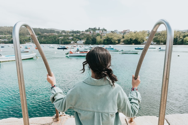 Woman backwards in front of the sea with a lot of boats during a sunny day