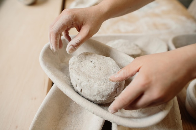 A woman baker kneads the dough and puts it in a wooden form Bakery concept