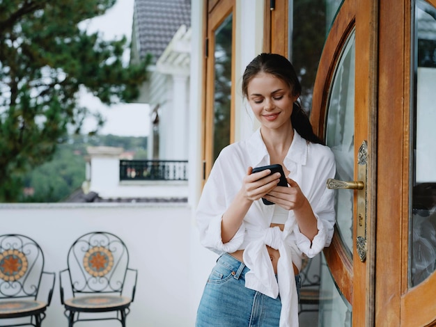 Woman on the balcony of the house with phone beautiful smile on a day off beautiful view of nature in the mountains lifestyle vacation in the hotel