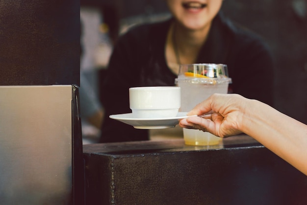 Woman barista serving cup of coffee at cafe