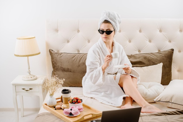 Woman in bathrobe after shower relaxing on the bed at home