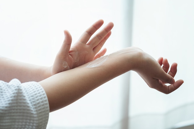 Woman in bathrobe applying moisturizing hand cream