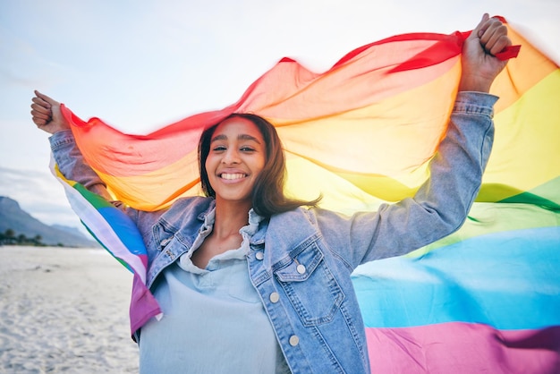 Woman beach and rainbow flag for lgbtq in portrait smile and wind with wave pride and equality for inclusion Student girl fabric or cloth for human rights lesbian sexuality or happy on vacation